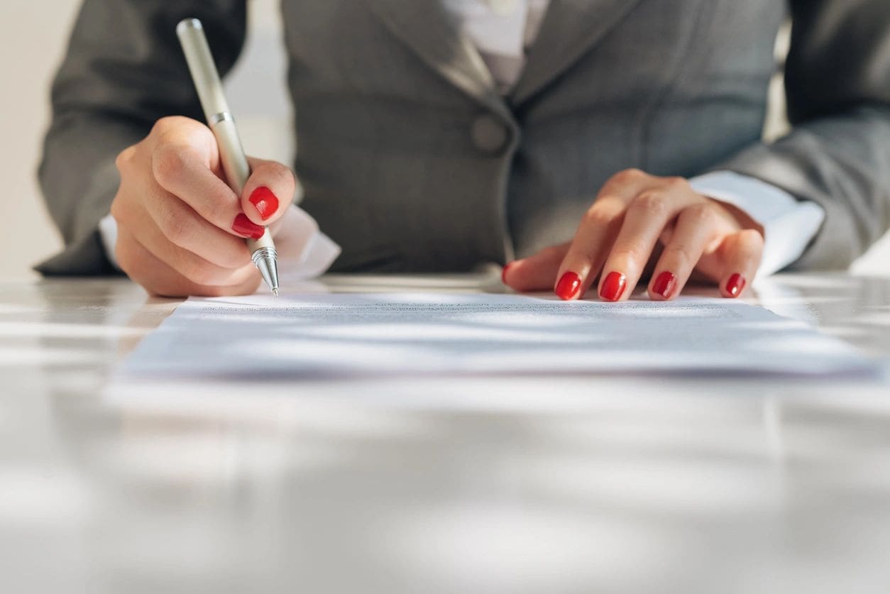 Person signing a document with pen.